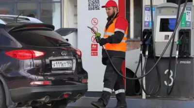 Сотрудник автозаправки у автомобиля